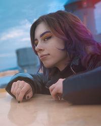 Close-up of young woman looking away while leaning on table