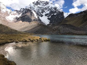 Scenic view of lake by snowcapped mountains against sky