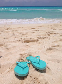 Deck chairs on sand at beach against blue sky