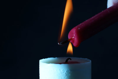 Close-up of lit candle against black background