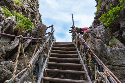 Low angle view of steps amidst rocks against sky