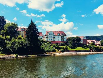 Houses by river against sky