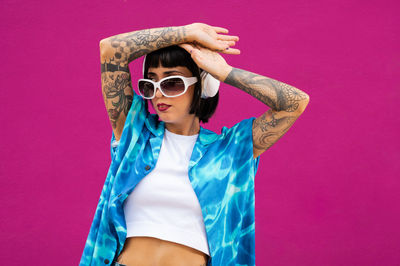 Young woman wearing sunglasses against yellow background