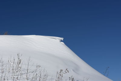 Low angle view of snowcapped mountain against clear blue sky