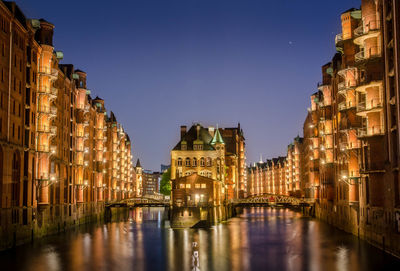 Canal amidst illuminated buildings in city at night