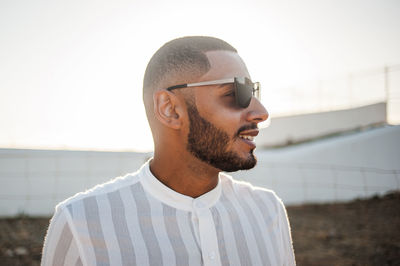 Close-up of young man wearing sunglasses standing against sky