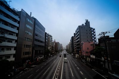 Road amidst buildings in city against sky