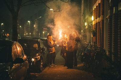 People standing by illuminated street in city at night