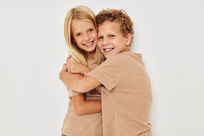 Portrait of smiling sibling against white background