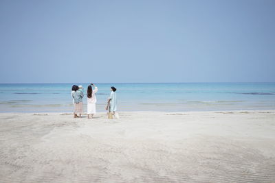 Women with baby at beach against clear sky