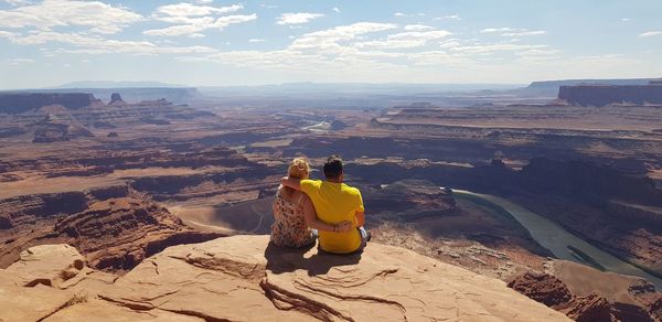 Rear view of people on rock formations against sky