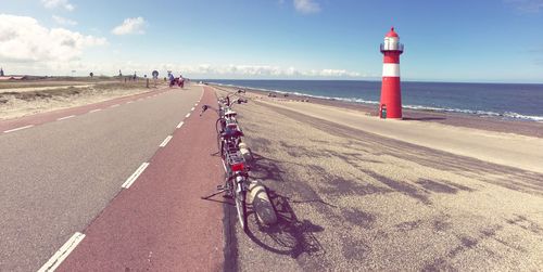 Bicycle by beach against sky