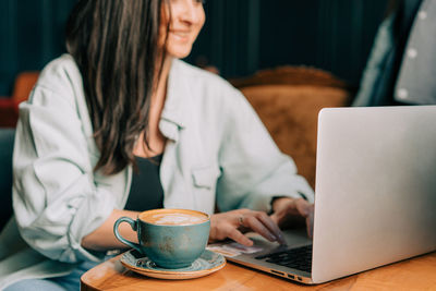 Young business woman drinking coffee while working on a laptop in a cafe.