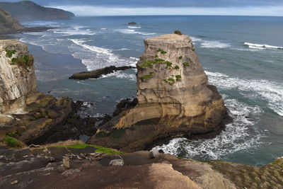 Rock formation on beach against sky