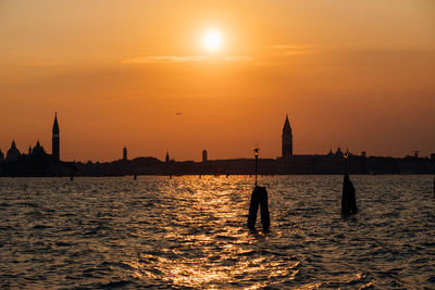 Sea in front of city against sky during sunset