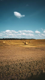 Scenic view of hay bales in the field and a blue sky