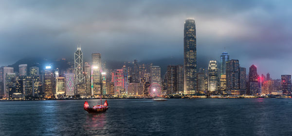 Illuminated modern buildings in city against sky