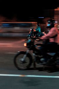 Blurred motion of people riding motorcycle on road