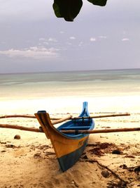 Boat moored on beach against sky