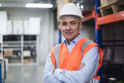 Portrait of man in factory hall wearing safety vest and hard hat