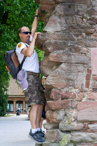 Full length of man wearing sunglasses standing against brick wall