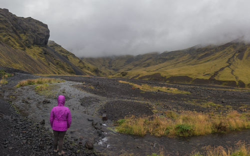 Rear view of woman walking on mountain against sky