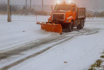 Snow covered road amidst field during winter