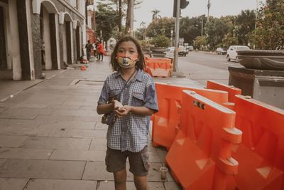 Portrait of teenage girl wearing mask begging on street