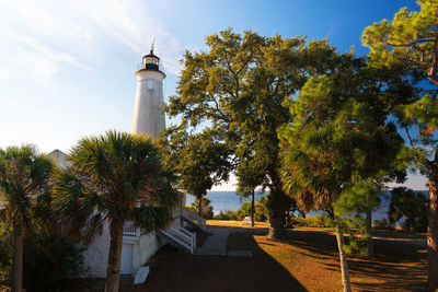 Lighthouse by trees against sky