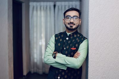 Portrait of young man standing against wall