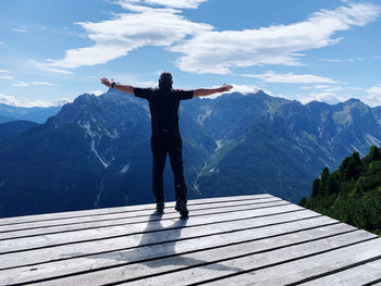 Rear view of man standing on mountain range against sky