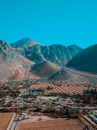 Aerial view of buildings and mountains against clear blue sky