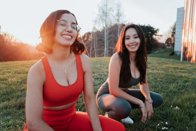 Portrait of smiling young females crouching at park
