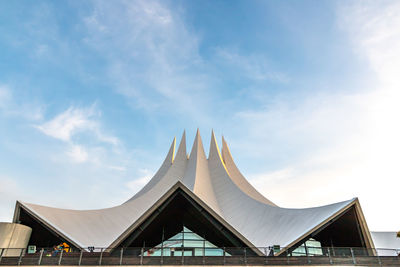 Low angle view of modern building against cloudy sky