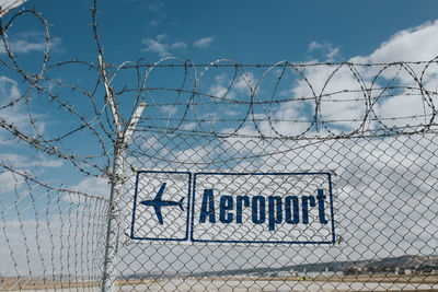 Text on chainlink fence against sky