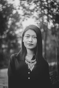 Portrait of young woman standing against tree