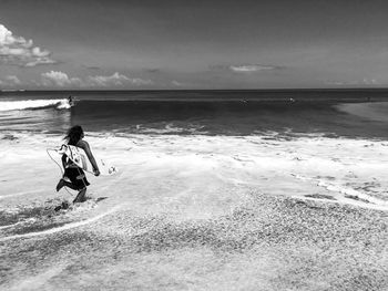 Rear view of boy on beach against sky