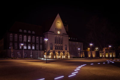 Illuminated city street against sky at night