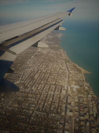 Airplane flying over city against sky