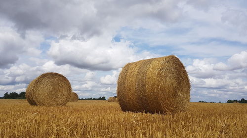 Hay bales on field against sky