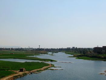 River amidst buildings in city against clear sky