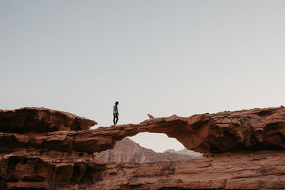 Mid distance of woman walking on rock formation against sky