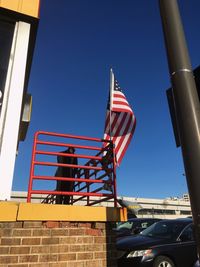 Low angle view of flags against clear blue sky