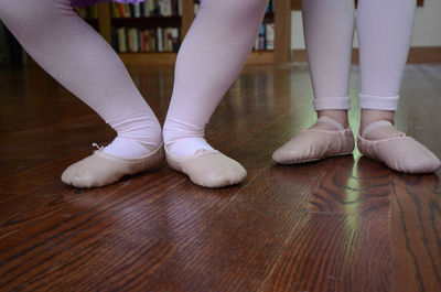 Low section of ballet dancers standing on hardwood floor