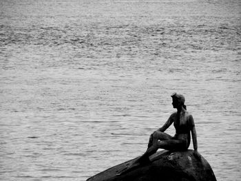 Man sitting on rock by sea