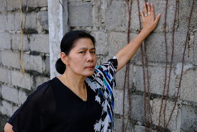 Mature woman wearing casuals while standing by wall