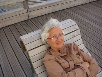 High angle portrait of woman relaxing on wooden deck chair