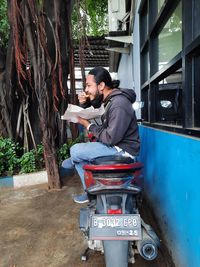 Full length of young man sitting on tree
