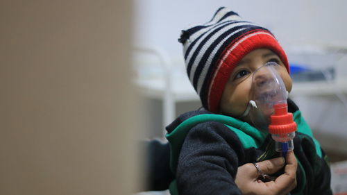 Close-up of baby with nebulizer sitting at hospital