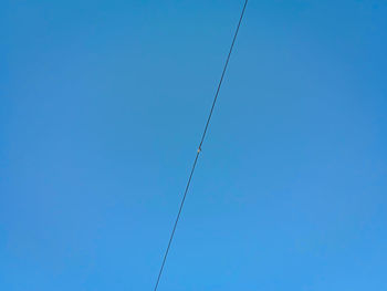 Low angle view of power lines against clear blue sky